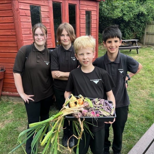 students show off the vegetables they have grown